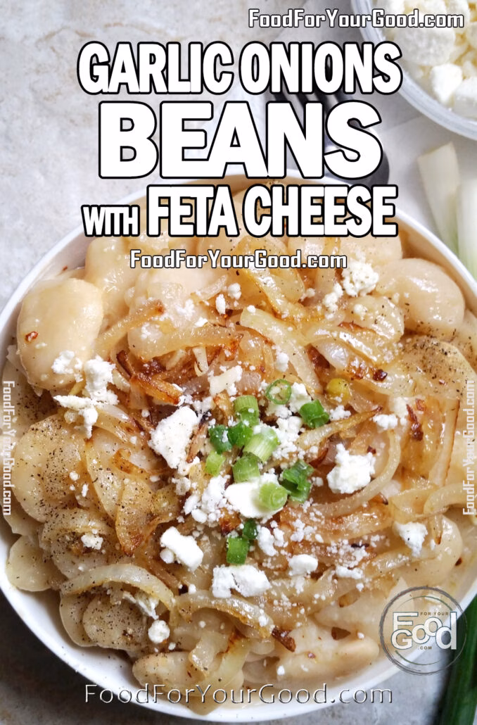 White beans topped with caramelized onions, garlic, crumbled feta cheese, and green onion garnish served in a white bowl on marble surface.