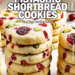 Stacked Cranberry Pistachio Shortbread Cookies with vibrant red cranberries and green pistachios, dusted with powdered sugar, displayed on a festive dessert table.