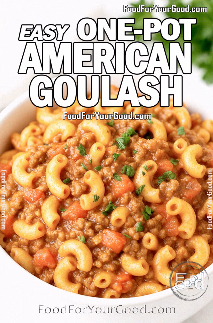 A white bowl filled with American goulash made with macaroni, beef, and tomato sauce, garnished with fresh parsley, on a white marble countertop with a towel and herbs in the background.