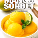Daylight photo of slightly melted mango sorbet in a white bowl, garnished with lime and mint, with a mango, ice cream scoop, and towel in the bright background.