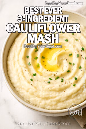 Creamy cauliflower mash topped with melted butter and chopped chives in a ceramic bowl on a marble surface.