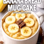 Easy Banana Bread Mug Cake topped with banana slices, a sprinkle of cinnamon, and chocolate chips in a white mug, photographed in a cozy, rustic setting.