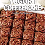 Freshly baked Double Chocolate Yogurt Coffee Cake in a white ceramic dish, topped with swirled milk chocolate glaze, sliced into twelve squares with yogurt, milk, white chocolate chips, and cocoa powder in the background.