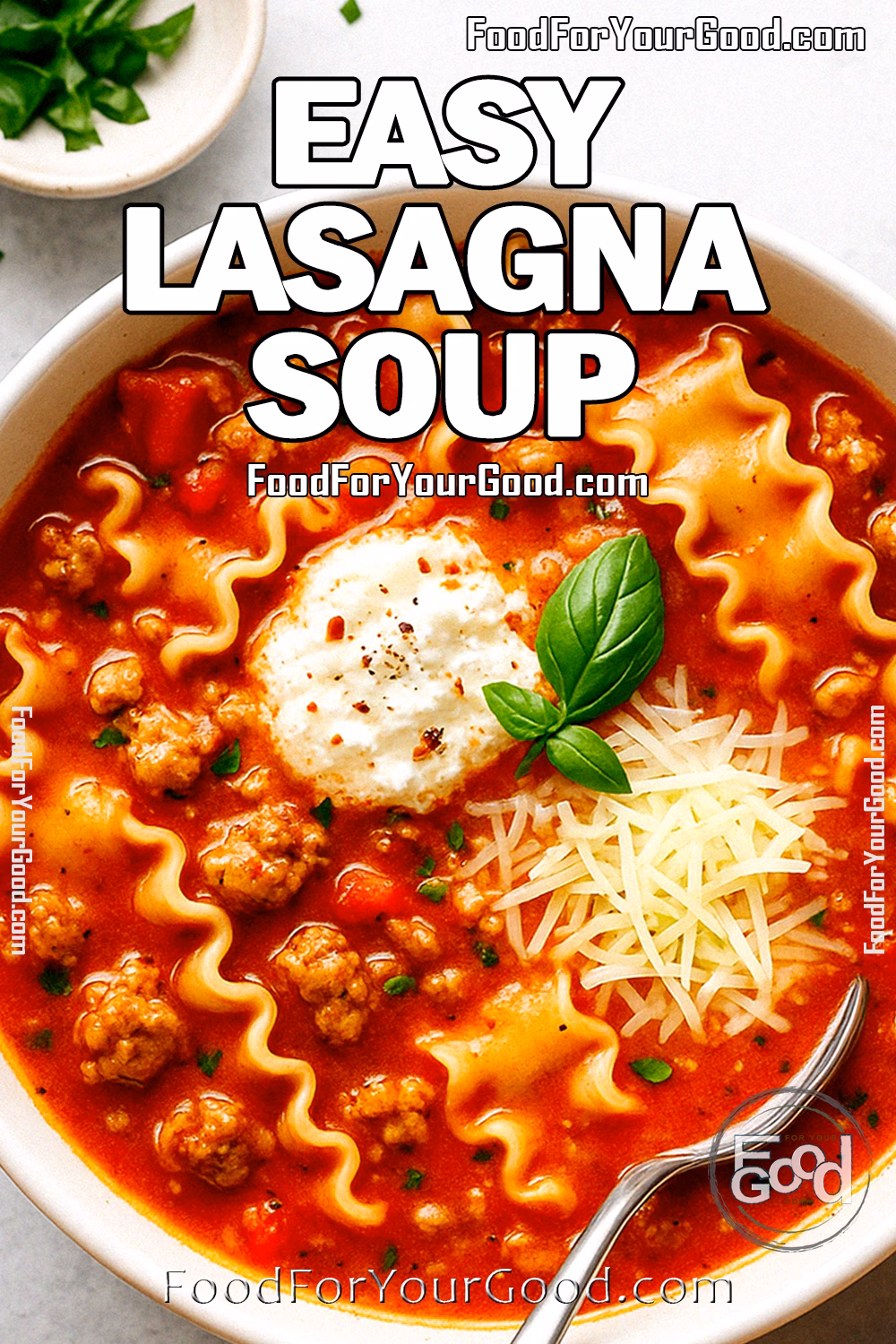 Easy Lasagna Soup Recipe | FoodForYourGood.com A bowl of Easy Lasagna Soup topped with ricotta, Parmesan, and basil, served with a spoon on a light background.