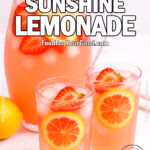 A refreshing pitcher and glasses of Strawberry Sunshine Lemonade with lemon slices and strawberries on a white marble background.