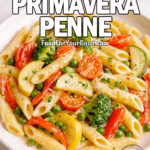 Creamy Primavera Penne served in a white bowl with fresh vegetables on a marble counter