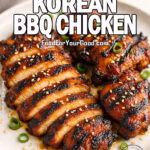 Sliced fire-grilled Korean BBQ chicken thighs with sesame seeds and green onions on a plate.