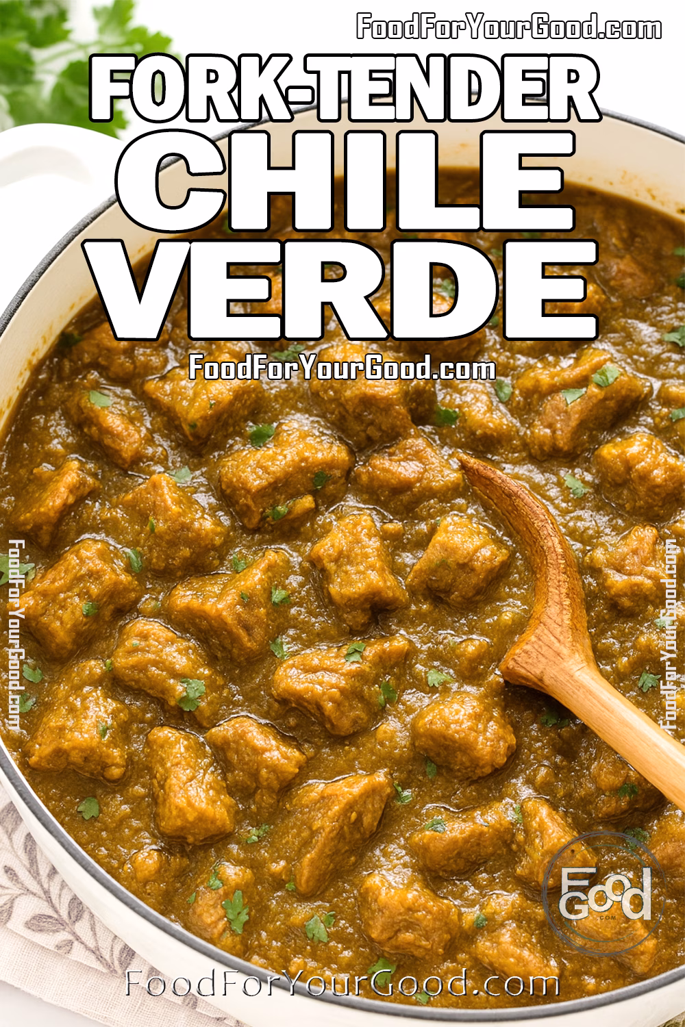 Fork-Tender Chile Verde in White Dutch Oven on FoodForYourGood.com A white Dutch oven filled with fork-tender pork chile verde in a thick green sauce, garnished with cilantro, with a wooden spoon and white towel beneath.