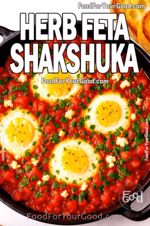 Herb Feta Shakshuka with eggs in tomato sauce, feta, and herbs in a cast iron skillet on marble background.