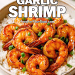 Crispy Honey Garlic Shrimp over white rice, garnished with green onions and sesame seeds in a rustic bowl from FoodForYourGood.com