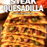 Stack of golden steak quesadilla wedges filled with melted cheese, jalapeños, and red onions, set on brown marble with sour cream and salsa.