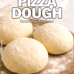 Three raw pizza dough balls resting on a wooden board dusted with flour, with a soft white towel in the background on a marble countertop.