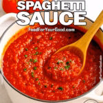 A white Dutch oven filled with rustic spaghetti sauce, garnished with parsley and stirred with a wooden spoon on a marble countertop.