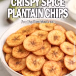 A beige ceramic bowl filled with air fryer crispy spice plantain chips, seasoned golden-brown and served on a white marble countertop with fresh green plantains and dipping sauce in the background.