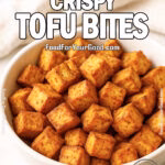 Crispy golden air-fried tofu cubes in a white bowl with dipping sauce on marble surface
