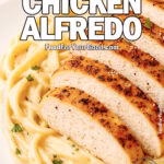 Creamy fettuccine Alfredo topped with golden sliced chicken breast, served on a white square plate.