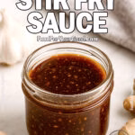 A jar of Better-Than-Takeout Stir Fry Sauce with garlic and ginger on a white marble counter