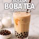 A glass of Brown Sugar Boba Tea on a white marble countertop, with tapioca pearls, brown sugar, and milk arranged nearby for a cozy, modern presentation.