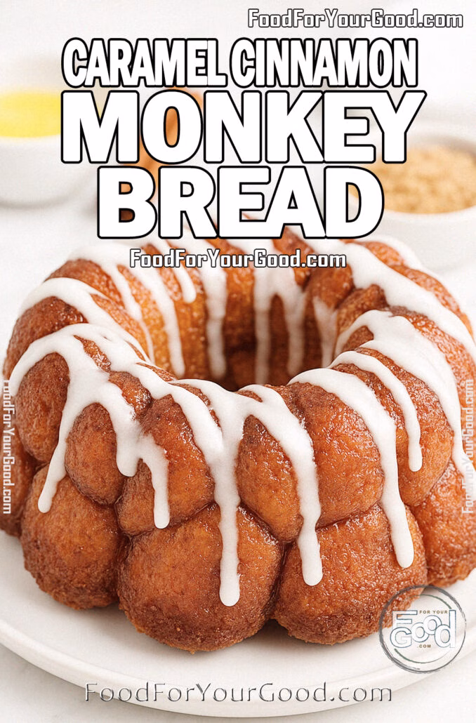 Caramel Cinnamon Monkey Bread Freshly baked Caramel Cinnamon Monkey Bread drizzled with powdered sugar glaze on a white plate, set on a marble countertop with cinnamon sticks, melted butter, and brown sugar in the background.