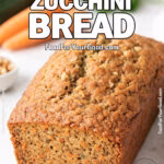 Carrot Zucchini Bread with a slice cut, on white marble cutting board, carrots and zucchini in background
