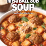 A cozy bowl of Cheesy Meatball Sub Soup with tender meatballs, melted cheese, toasted baguette cubes, and fresh basil served on a white marble surface.