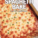 Baked spaghetti casserole topped with golden melted cheese and parsley in a white ceramic dish on a marble countertop.