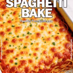 Baked spaghetti casserole topped with golden melted cheese and parsley in a white ceramic dish on a marble countertop.