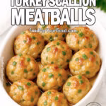 White oval dish filled with moist, golden roasted turkey meatballs brushed lightly with butter for shine, with mozzarella peeking through and scallions inside, garnished with finely chopped scallions. Set on a white marble background with fresh parsley and a white towel blurred in the background.