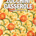 Freshly baked Cheesy Zucchini Casserole in a white ceramic dish, topped with golden cheese, zucchini slices, cherry tomatoes, and fresh basil.