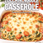 A freshly baked Cheesy Zucchini Noodle Casserole in a white square dish, topped with golden melted mozzarella and Parmesan, surrounded by fresh zucchini, tomatoes, spinach, and marinara sauce on a white marble countertop.