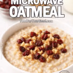 A white bowl filled with creamy Cinnamon Maple Microwave Oatmeal topped with cranberries and walnuts on a marble countertop.