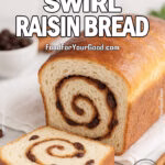 Cinnamon Swirl Raisin Bread sliced to show cinnamon sugar spiral, with raisins and cinnamon sticks on marble countertop.