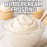 Clear glass bowl of Classic American Buttercream Frosting on a marble tray with a spoonful of frosting beside it, cupcakes in the blurry background, photographed in bright daylight on FoodForYourGood.com