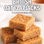 Classic British Oat Flapjacks stacked on a white marble tray with a cup of tea in the background, styled on a marble surface for FoodForYourGood.com