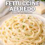 Classic Creamy Fettuccine Alfredo on white plate with Parmesan, garlic, and parsley on marble background.
