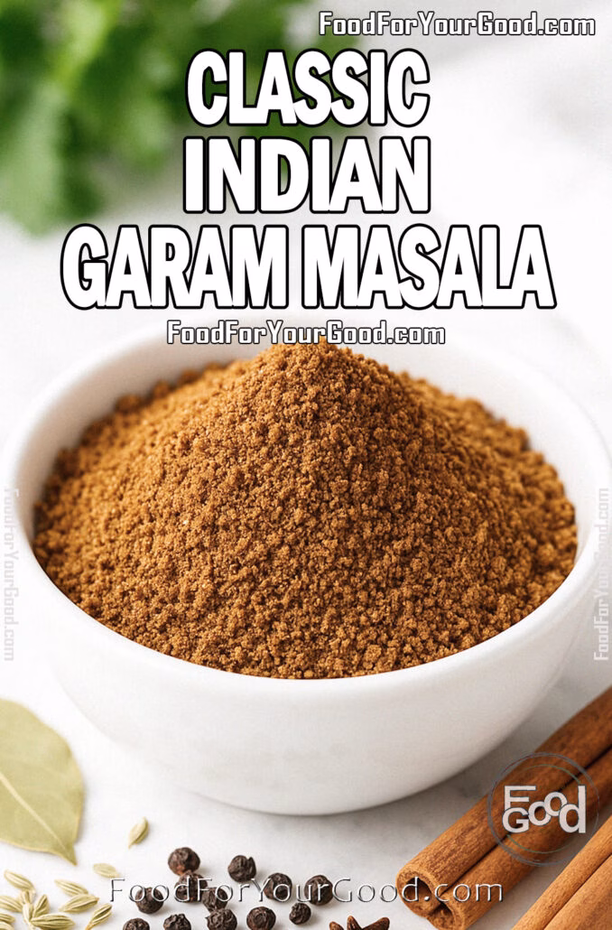 Classic Indian Garam Masala A bowl of freshly ground Classic Indian Garam Masala with cinnamon sticks, cloves, peppercorns, fennel seeds, and a bay leaf on a white marble surface, with a blurred white towel and green herbs in the background.