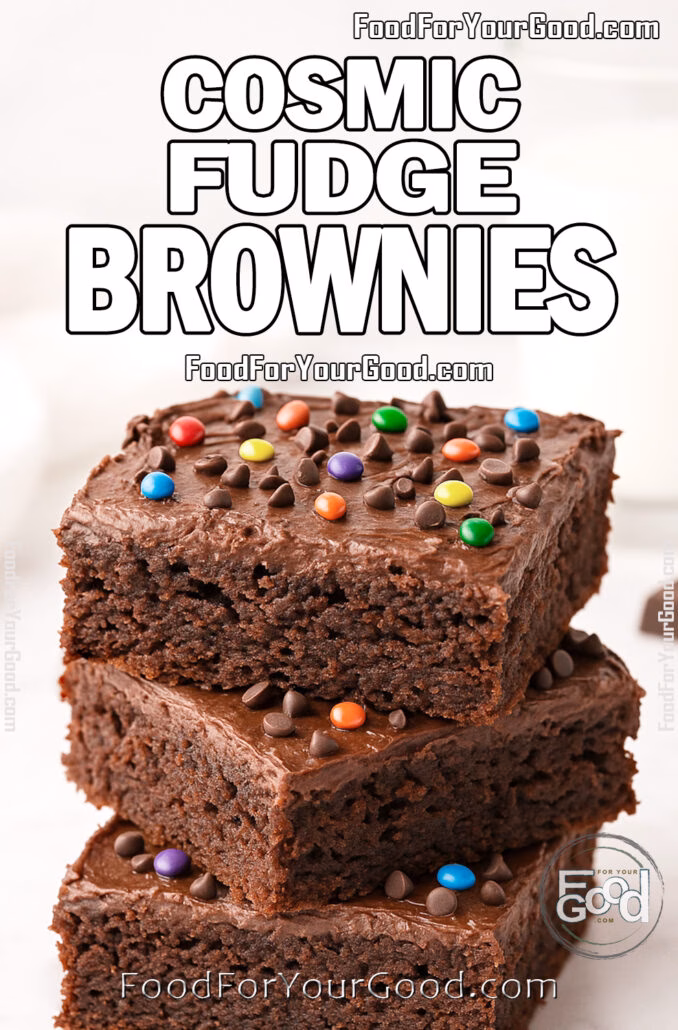 Homemade Cosmic Fudge Brownies with ganache frosting, colorful chocolate pieces, and a glass of milk on white marble