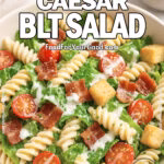 Creamy Caesar BLT Salad in a white bowl with pasta, bacon, lettuce, and cherry tomatoes on a marble background.