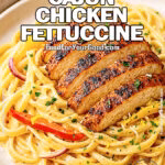 Creamy Cajun Chicken Fettuccine topped with sliced blackened chicken and bell peppers on a white plate.