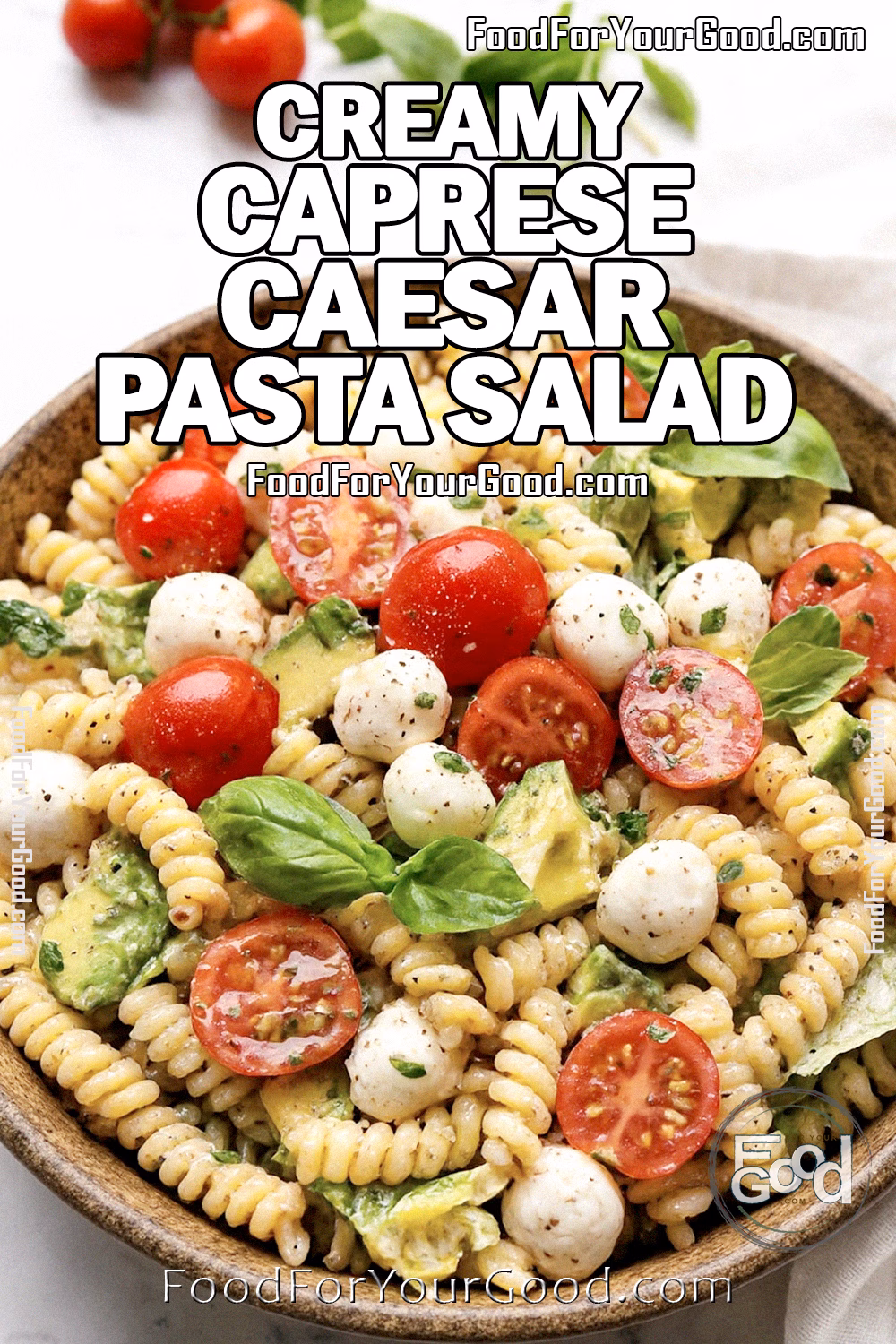 Creamy Caprese Caesar Pasta Salad with rotini, cherry tomatoes, mozzarella, basil, and Caesar dressing served in a rustic bowl on white marble at FoodForYourGood.com