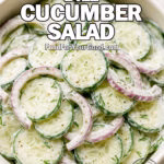 Creamy Dill Cucumber Salad in a white ceramic bowl with red onions and fresh dill on marble background