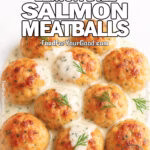 Golden salmon meatballs drizzled with creamy lemon-dill sauce, garnished with fresh dill and lemon, on a white marble background.