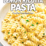 A close-up of Creamy Lemon Ricotta Pasta in a rustic white bowl, topped with herbs and lemon zest.