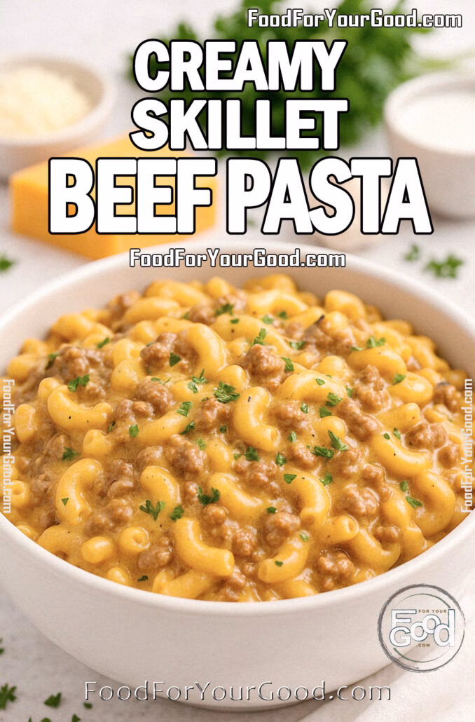 Creamy Skillet Beef Pasta in a white bowl on marble with cheddar, parsley, and onion in background