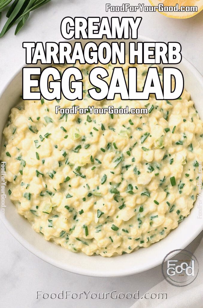 Overhead view of Creamy Tarragon Herb Egg Salad in a white bowl with fresh herbs and lemon on marble at FoodForYourGood.com