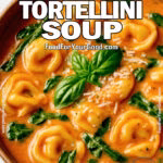 Bowl of creamy tomato tortellini soup with spinach and Parmesan in a rustic ceramic bowl on a marble countertop.