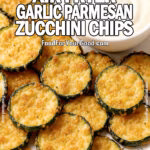 Crispy Air Fryer Garlic Parmesan Zucchini Chips on a white plate with a bowl of creamy dipping sauce, showing slightly uneven sizes, soft edges, and a golden breadcrumb coating.
