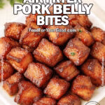 Juicy and crispy Air Fryer Pork Belly Bites on a white square plate, golden brown with caramelized edges and glossy texture, garnished with parsley and styled with herbs and a towel in the background on FoodForYourGood.com