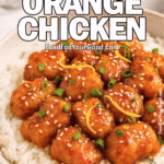 Crispy Orange Chicken served over jasmine rice, garnished with sesame seeds and green onions in a ceramic bowl on marble