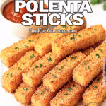 Crispy Parmesan Polenta Sticks on marble cutting board with parchment paper and homemade-style pieces served with marinara.